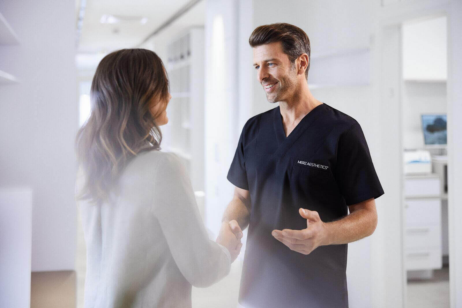 Een esthetisch specialist schudt de hand van een patiënte.